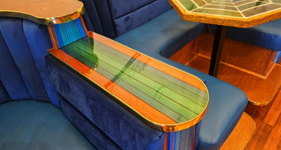 Velvet booth with an inlaid wood and resin table edge