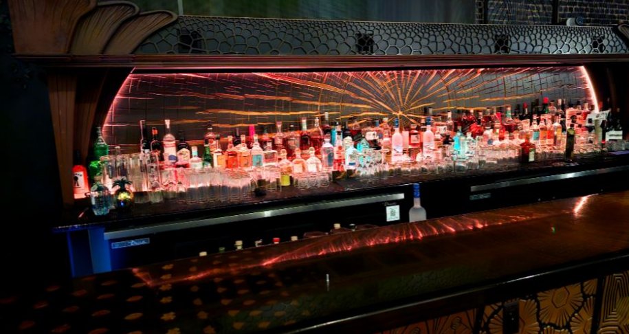 Backlit bar with a radiating light display behind the bottles