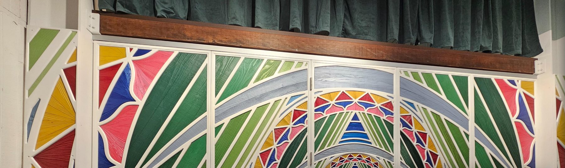 Folding divider wall with a jewel-toned lattice of painted reclaimed wood