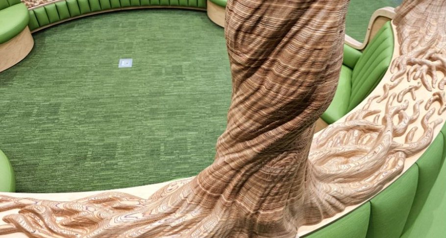 Twisting layered-plywood trunk above the green bench